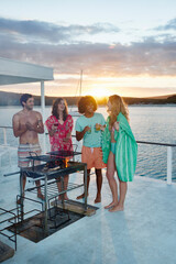 Wall Mural - Young adult friends barbecuing, hanging out drinking on summer houseboat at sunset