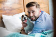 Portrait smiling man petting Jack Russell Terrier dog on bed