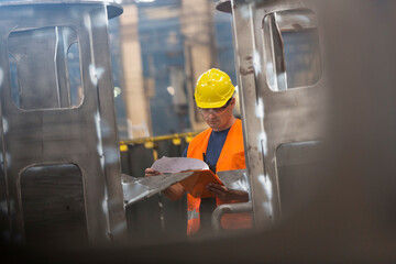 Poster - Steel worker reviewing paperwork in factory