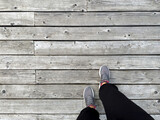 Fototapeta Desenie - Legs in sneakers on a wooden platform. There is space for text.