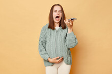 Despair Shocked Scared Pregnant Woman Wearing Knitted Sweater Standing Isolated Beige Background Holding Smartphone Recording Voice Messages Calling Doctor Screaming Feeling Pain.