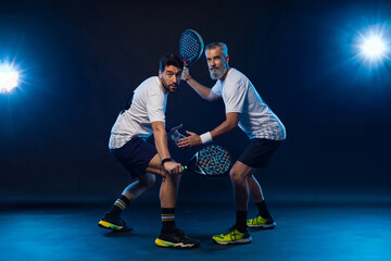 Wall Mural - Padel tennis doubles. Two athletes players with racket. Man athlete with paddle racket on court with neon colors. Sport concept. Download a high quality photo for the design of a sports app