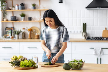 Young Asian woman cooking healthy food while standing in the kitchen at home. Healthy lifestyle concept