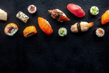 Sushi, Shot From The Top. Rolls, Maki, Nigiri On A Black Slate Background, Japanese Food. Salmon, Eel, Shrimp, Tuna Etc With Rice, With A Place For Text
