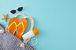 Safe suntanning concept on vacation. Top view composition of sunscreen lotion, striped bag, flip-flops, sunglasses, starfish, shell bracelet on light blue background with empty space for promo or text