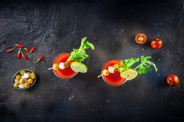 Bloody Mary cocktail with garnish on a black background, overhead flat lay shot with copy space. Spicy tomato juice with alcohol, lime, pickles