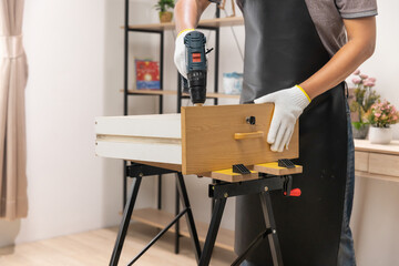 Worker repair wooden drawer of cabinet in living room.