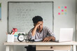 © Queenmoonlite Studio - Frustrated tired high school teacher sitting on desk in classroom