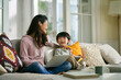 © imtmphoto - happy asian mother and son sitting and chatting on couch at home