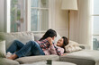 happy asian mother and daughter lying on couch and chatting at home