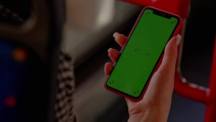 Women's hands hold a smartphone with a green screen in their hands. The use of modern gadgets in public transport.