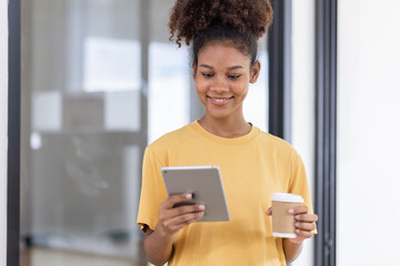 Wall Mural - Young pretty employee business african american woman work in office with tablet pc computer. Concept of surfing web with browse use pad gadget