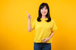 © Jirawatfoto - Confident Asian woman pointing to free copy space isolated on yellow studio background