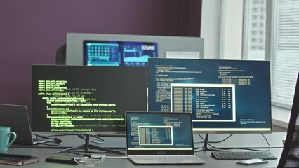 No people shot of program codes on two desktop computers and laptop on desk in cyber security agency