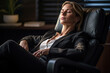 © ADDICTIVE STOCK - Generative AI image of mature female relaxing in armchair at workplace with closed eyes on blurred background at night