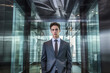 © ADDICTIVE STOCK - Generative AI illustration of young male executive in elegant suit looking at camera while standing with hands in pockets against glass building