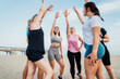 © okrasiuk - Happy fitness class giving high five after completing workout on beach. Multi aged women motivated after session together, engaged in team building, join hands for shared goal or success at training