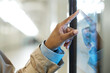 Focus on hand of young African American woman pointing at display with route map of subway trains while standing in front of touchscreen