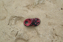 Black And Red Children Shoe Lost On The Sandy Beach