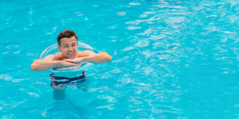 Wall Mural - Portrait of a cheerful middle-aged man in the pool with inflatable lifebuoy.