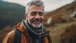 © IC Production - Happy male hiker smiling while standing alone. Cheerful mature man carrying a backpack and standing on a hilltop. Adventurous backpacker enjoying a hike at sunset.
