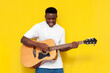 © Богдан Маліцький - joyful african american man holds acoustic guitar and sings on yellow isolated background
