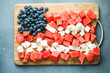 Patriotic salad idea with blueberries, feta and watermelon in the shape of American flag on gray background, USA Independence Day, Top view