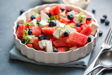 Summer salad with watermelon, feta cheese and blueberry on a gray background. Vegan, European food.