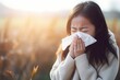 Young Asian Woman with Tissue Blowing her Nose Managing Symptoms from Cold or Allergies