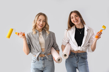 Canvas Print - Young women with wallpapers and rollers on grey background