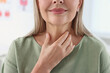 © New Africa - Endocrine system. Senior woman doing thyroid self examination indoors, closeup