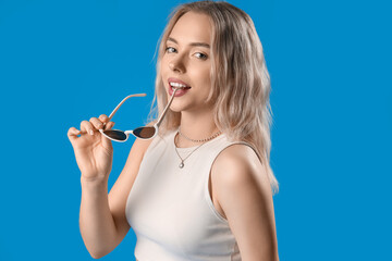 Poster - Young woman with stylish sunglasses on blue background