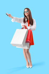 Sticker - Young woman with gift card and shopping bags on blue background