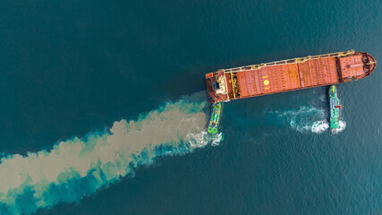 Aerial top view of cargo ship carrying container and running with tug boat for import export goods from cargo yard port to custom ocean concept freight shipping by ship .