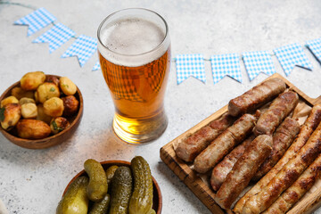 Glass of cold beer and different snacks on light background. Oktoberfest celebration