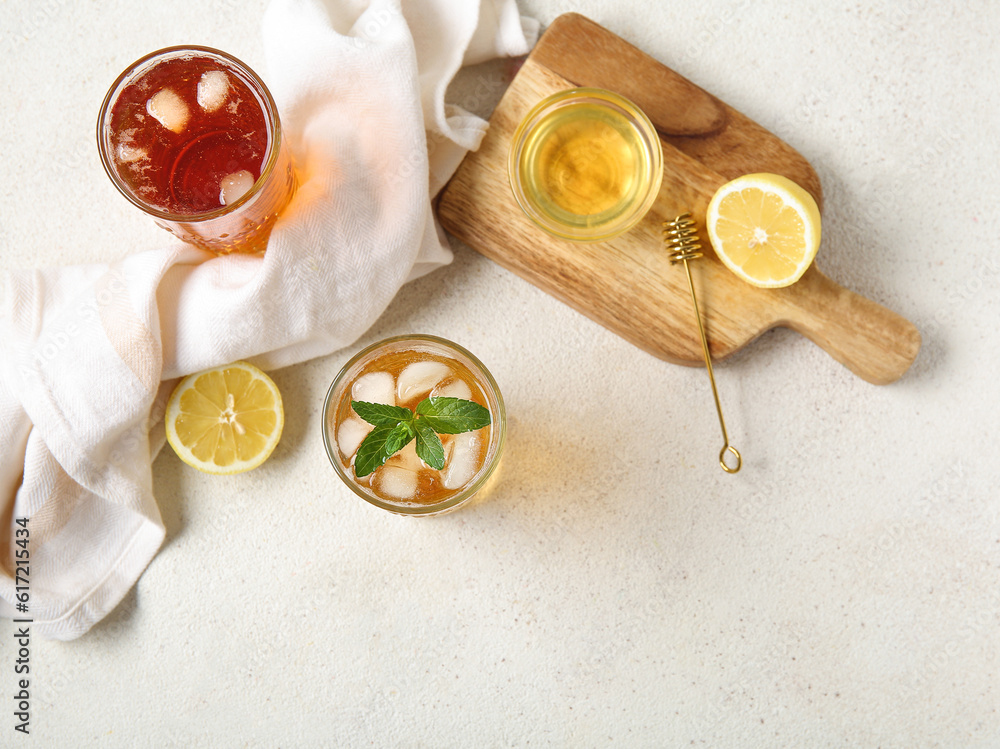Glasses of ice tea and board with lemon on white background