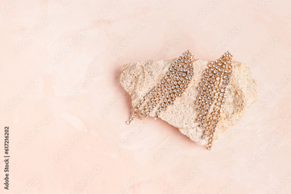 Stone with beautiful earrings on pink background
