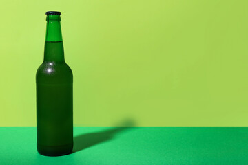 Bottle of cold beer on green background