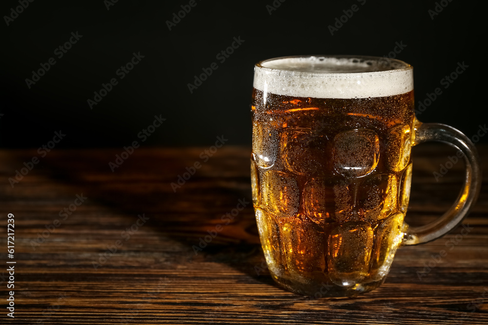 Mug of cold beer on wooden table