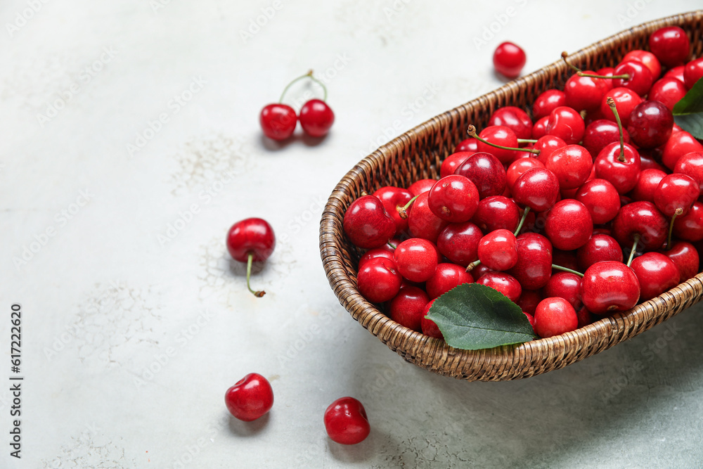 Wicker bowl with sweet cherries on white background