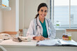 © tigercat_lpg - Portrait of beautiful female doctor and professional nutritionist in uniform smiling and looking at camera with supplementary foods on desk for healthy diet at hospital.