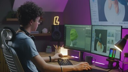 Teenage 3D designer develops video game, creates character or clothes, works remotely from home on PC and big digital screen with professional software interface and tools for 3D modeling and design.