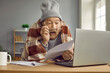 © Studio Romantic - Stressed elderly man in warm clothes and glasses sits at desk at home in cold apartment, holds domestic utility bill, reads information, looks at figures shocked by expensive Internet or heating costs