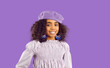 Portrait of cute beautiful stylish dark skinned preteen girl on light purple studio background. Ethnic smiling little pretty kid lady with curly hair dressed in beret, massive earrings and blouse.