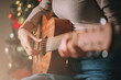 Close up on hand of woman musician playing acoustic guitar at home party at night with bokeh background