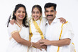© G-images - Smiling south indian parents and daughter posing in traditional clothing.