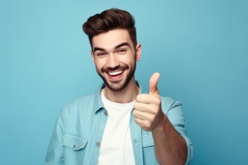 Portrait of happy young man showing thumbs up gesture on blue background, Generative AI