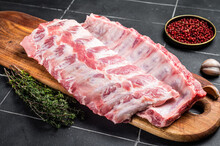 Fresh Pork Spareribs, Raw Spare Loin Ribs On A Wooden Board With Thyme And Spices. Black Background. Top View