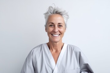 Wall Mural - Portrait of happy senior female doctor smiling at camera on white background