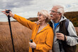 © Zoran Zeremski - Active senior couple with backpacks hiking together in nature on autumn day..